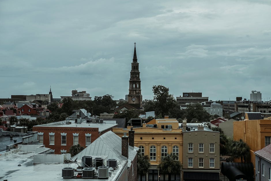 A picturesque view of Charleston, SC, featuring a historic church tower amidst vibrant buildings.