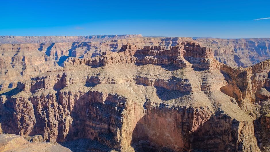 Majestic Grand Canyon landscape with rugged cliffs against clear blue sky.