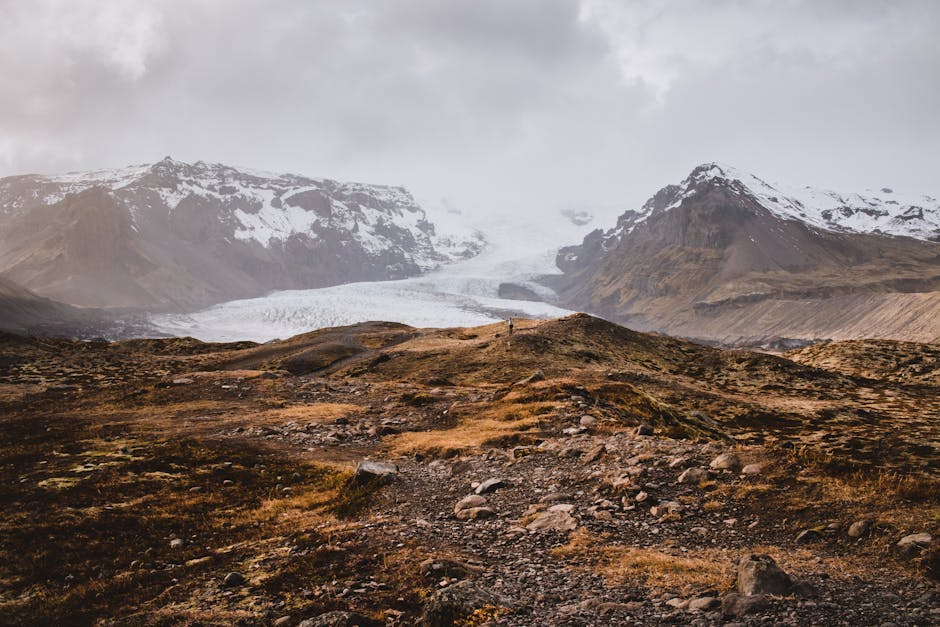 A stunning view of an Icelandic glacier amidst rugged terrain and autumn colors.