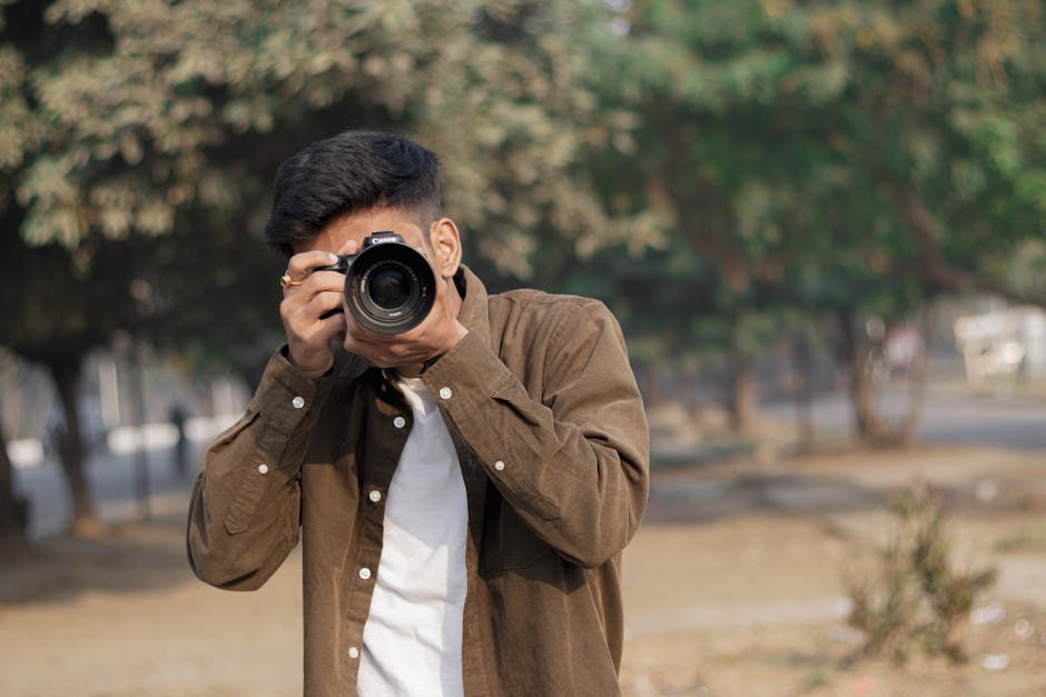 Young man with DSLR camera capturing moments outdoors on a sunny day.