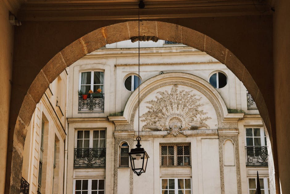 View of ornate Parisian building facade framed by an archway with a decorative lantern.