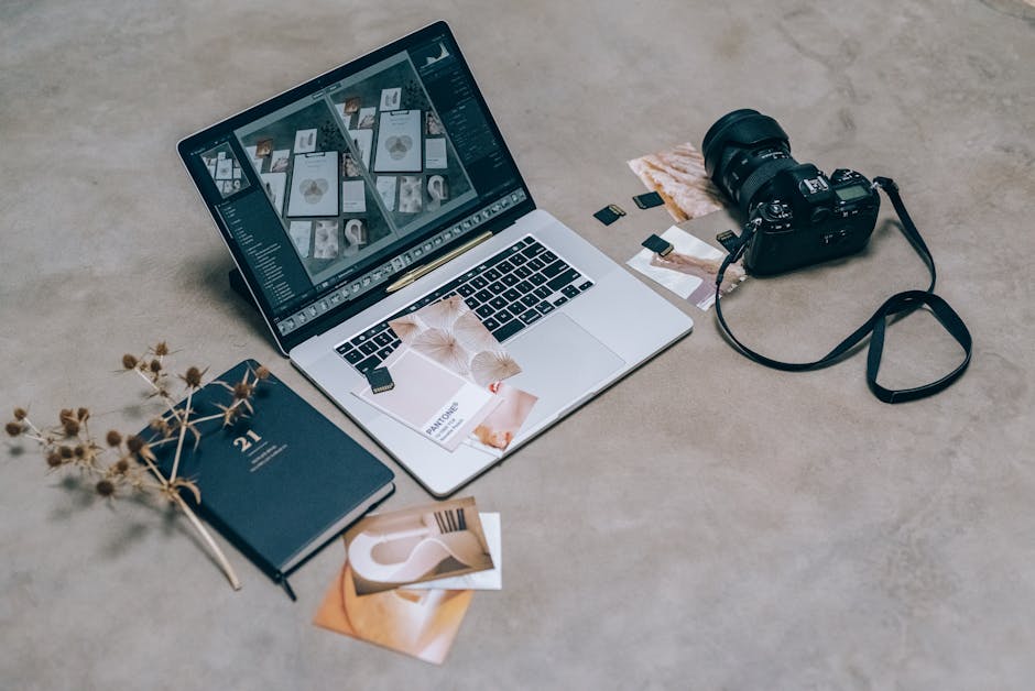 Top view of a creative workspace featuring a laptop, camera, and design materials, ideal for digital artists.