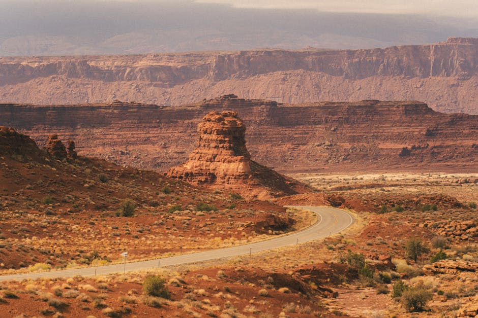A winding road through Utah's iconic red rock formations under a dramatic sky.
