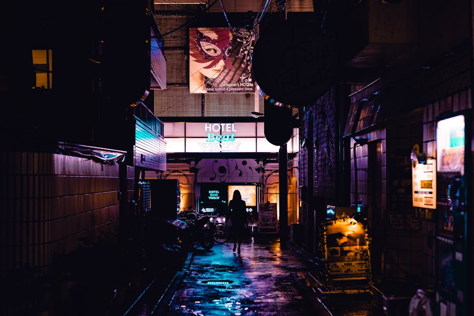 Silhouette of a person walking in a vibrant, neon-lit alleyway in Shinjuku, Tokyo at night.