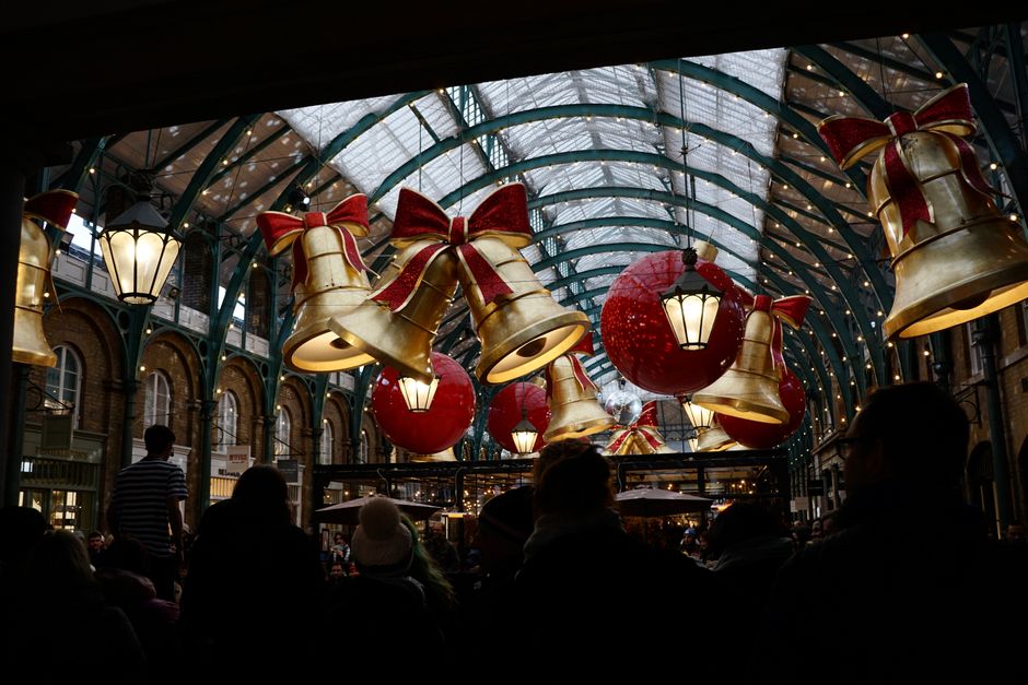 A vibrant scene of Christmas decorations in Covent Garden Market, London, with festive bells and ribbons.