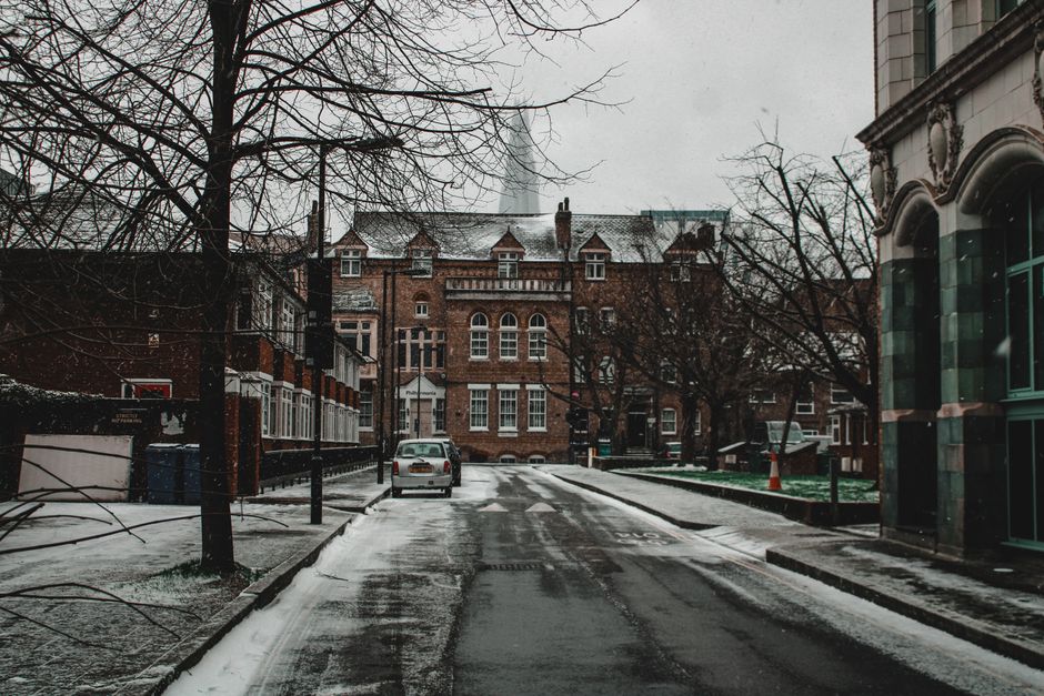 A moody winter street scene in Southwark, London, featuring snow-covered roads and historic architecture.