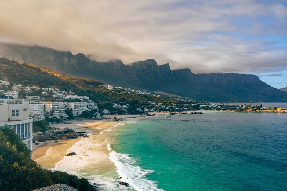 Beautiful coastal view of Cape Town with mountains and beach under dramatic sky.