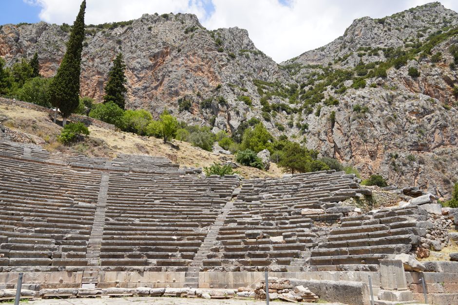 Explore the ancient ruins of the Greek theater at Delphi, nestled in the mountainous landscape.