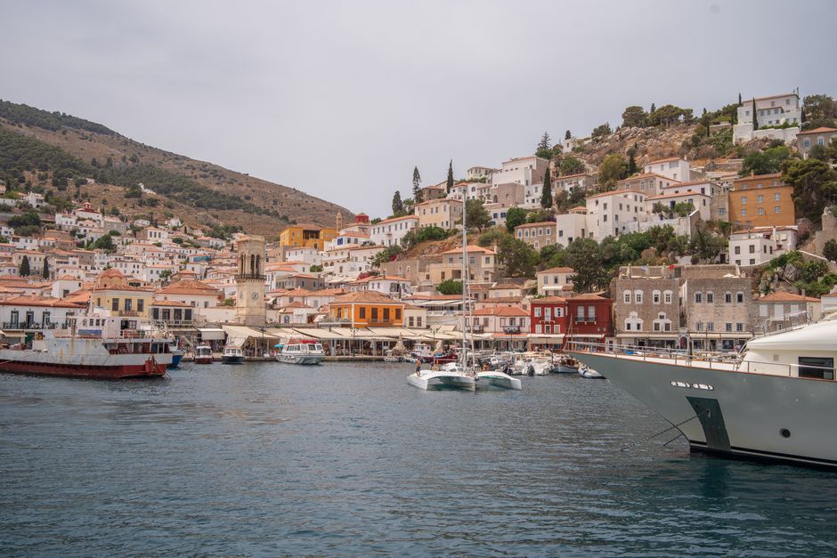 Charming Hydra Island harbor with colorful houses and yachts on a sunny day.