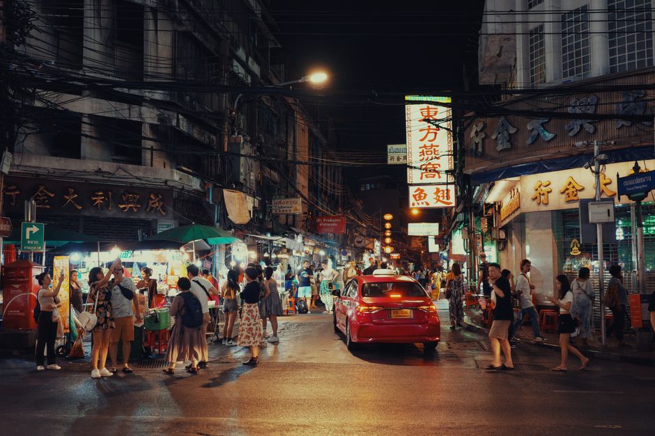 A lively and bustling Asian street market at night with vibrant lights and crowds.