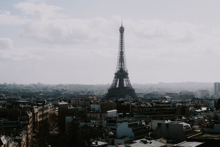 A stunning view of the Eiffel Tower rising above the Paris cityscape under a cloudy sky.