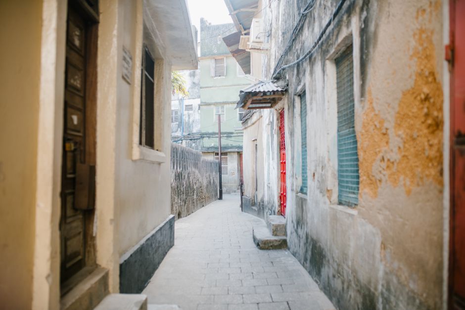Paved narrow street between aged stone residential houses with shabby facade in city
