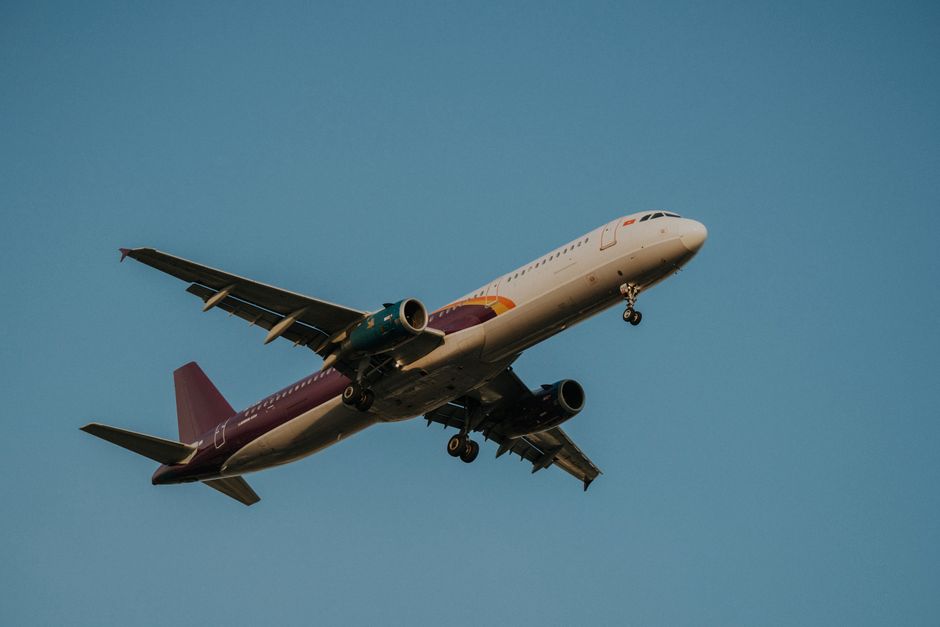 Low-angle view of a commercial airplane flying against a clear blue sky, showcasing its wings and fuselage.