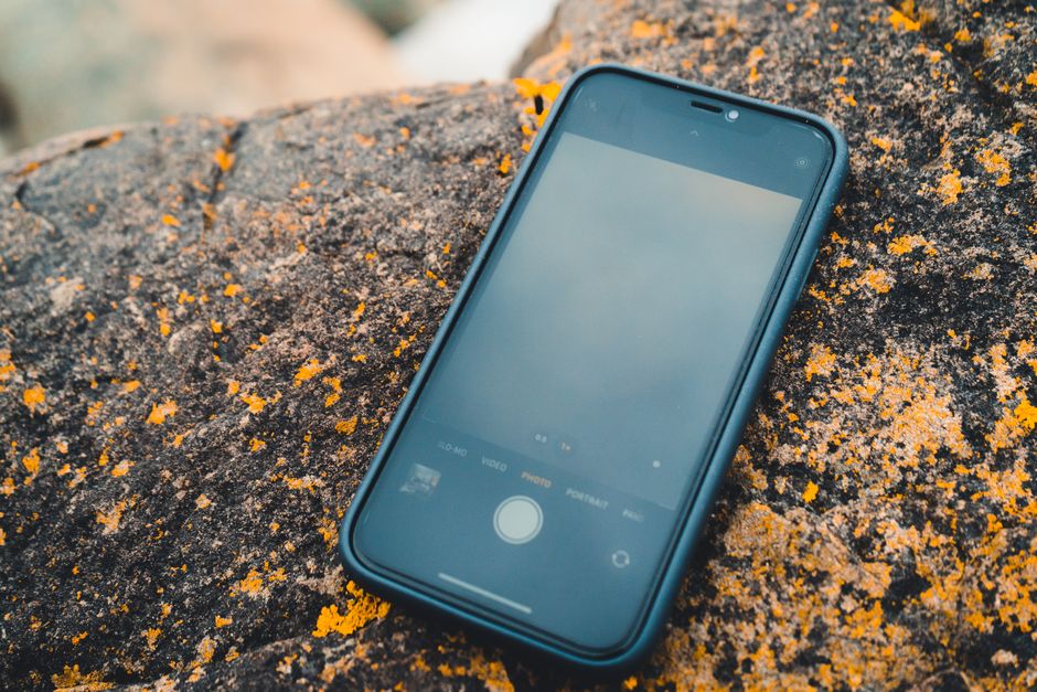 A smartphone lying on a lichen-covered rock, blending technology with nature.
