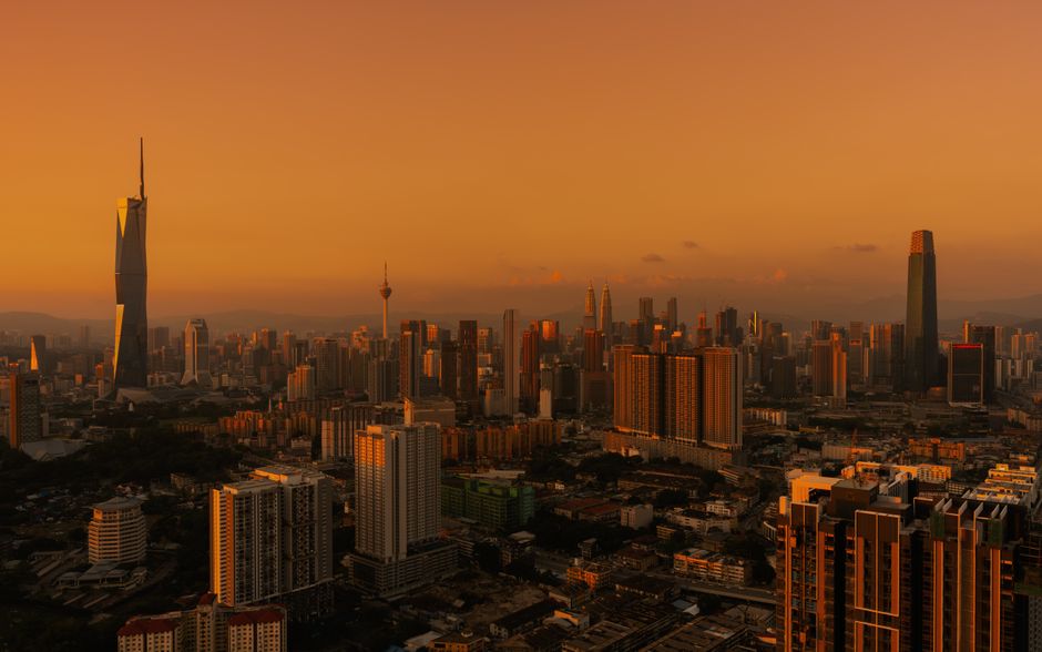 Stunning aerial view of Kuala Lumpur skyline under a warm, golden sunset.