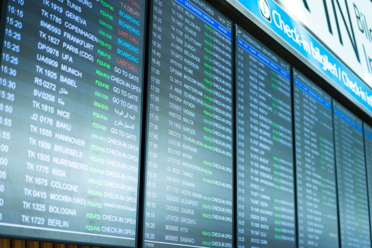 Digital screens display flight information and schedules at an airport terminal.