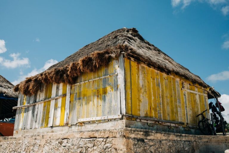 A traditional wooden hut with a thatched roof in Mexico against a clear blue sky.