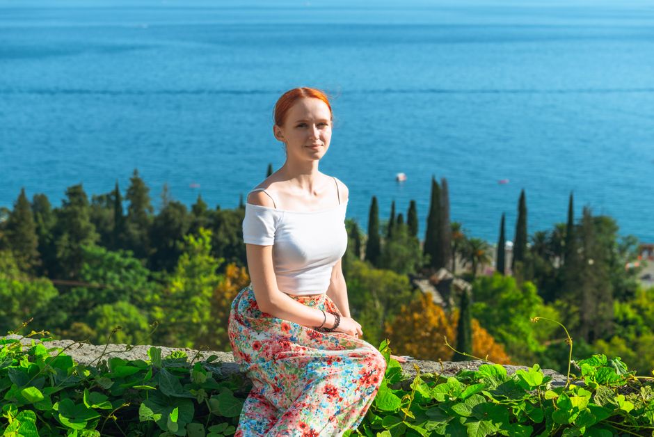 Woman relaxing on a sunny day in Gagra with a stunning sea view, showcasing joy and serenity.