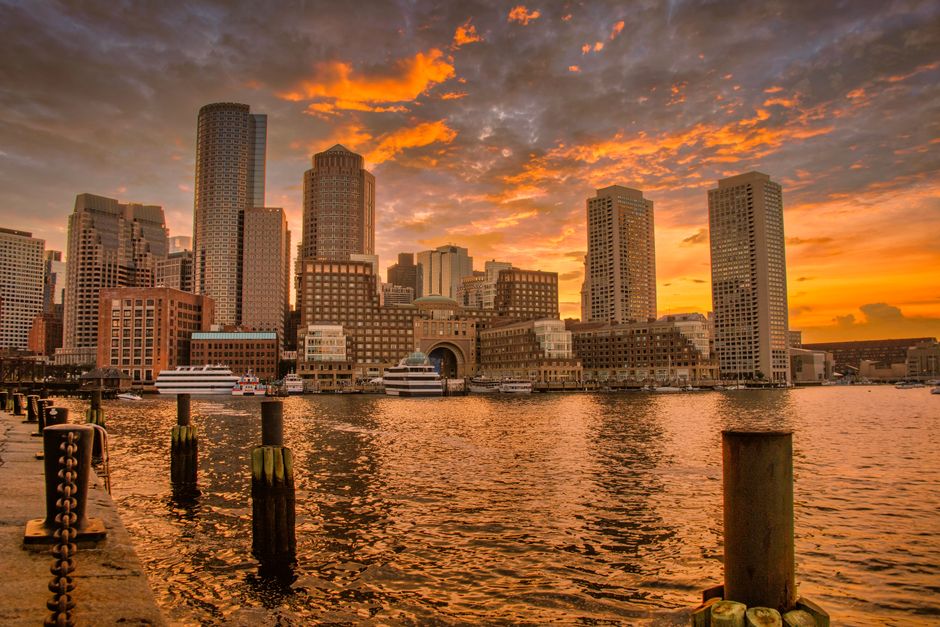 Stunning sunset over Boston's iconic skyline reflecting in the harbor waters.
