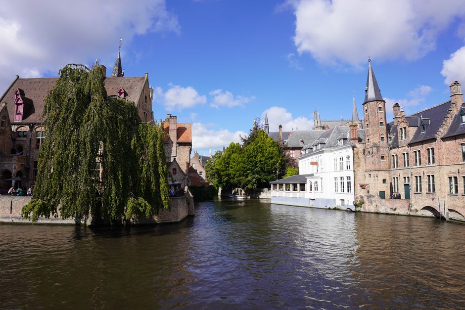 Picturesque canal scene with historic architecture in Bruges, Belgium under a blue sky.