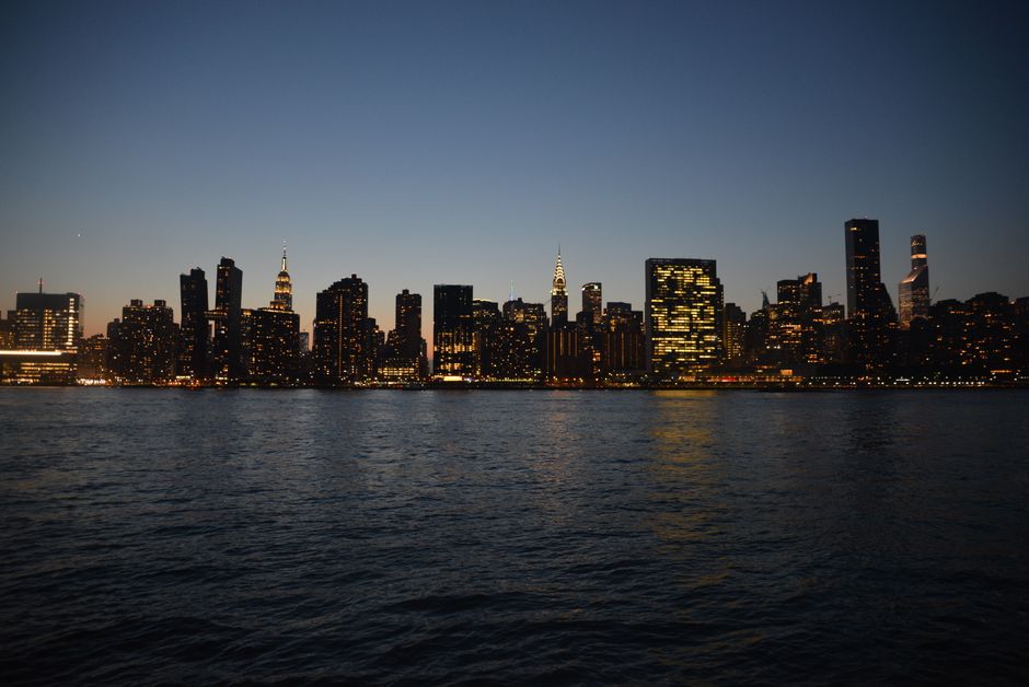 Stunning New York City skyline captured at dusk with illuminated skyscrapers reflecting in the water.