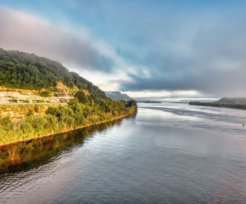 Breathtaking view of the Mississippi River's lush banks under cloudy skies in Minnesota.