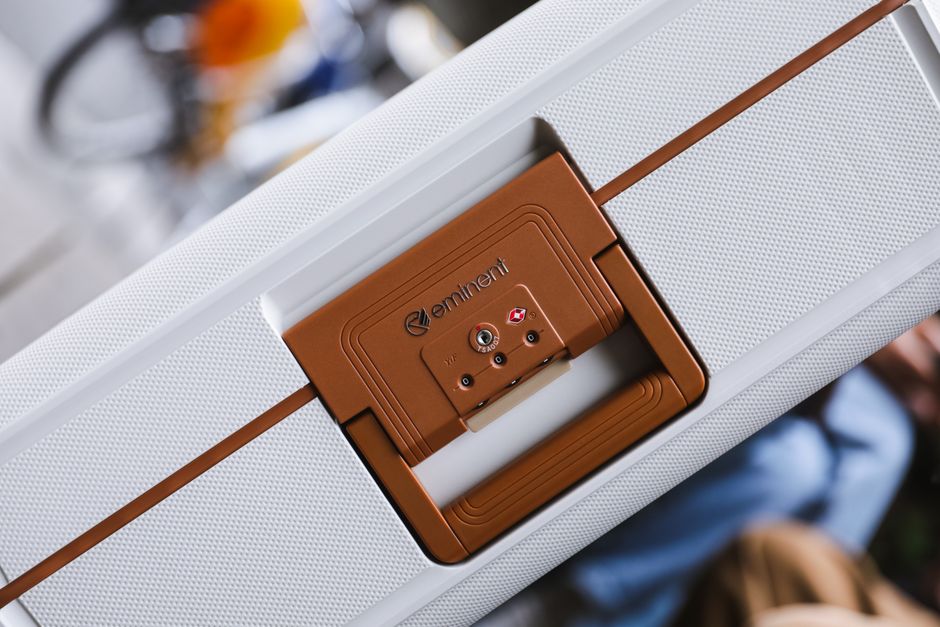 Close-up of a brown-handled white suitcase with a TSA lock, emphasizing travel security.