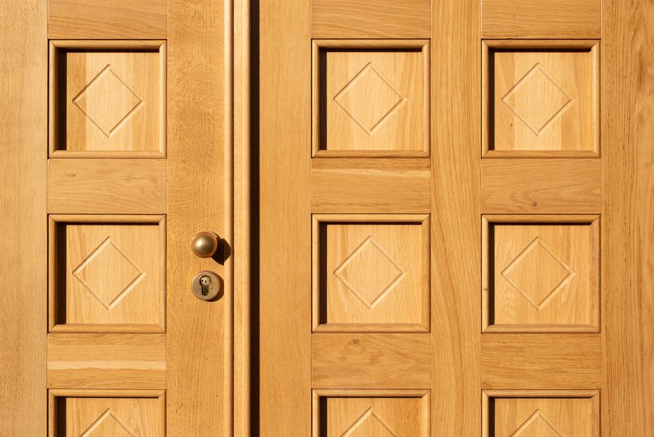 Close-up of a wooden door featuring geometric diamond patterns and a brass handle.