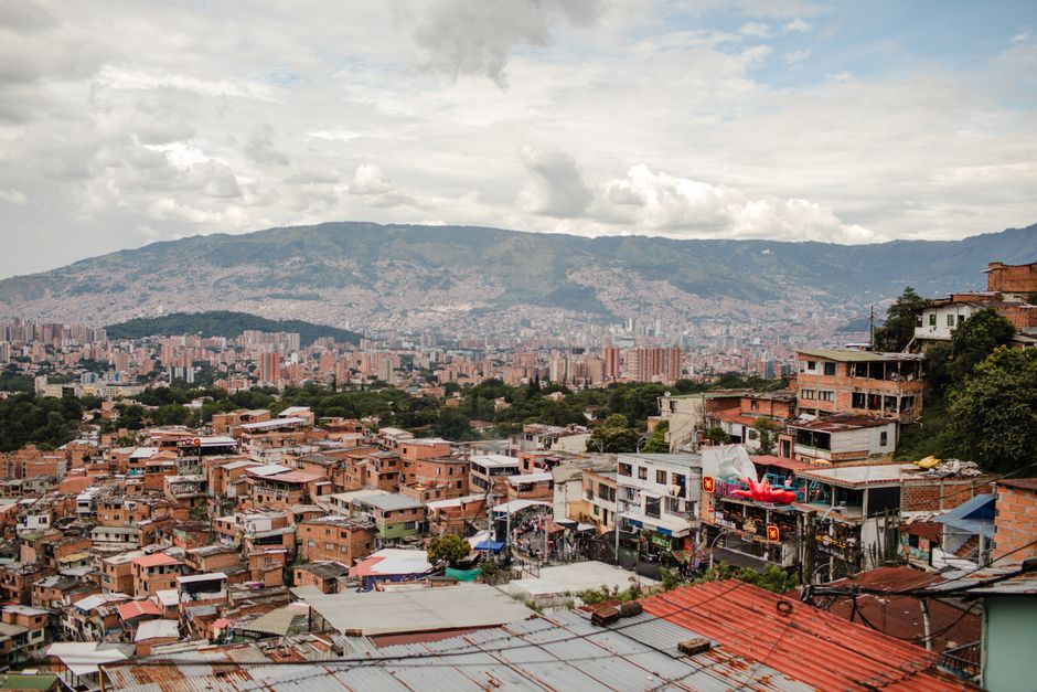 Stunning cityscape of Medellín with vibrant rooftops and distant mountains under a cloudy sky.