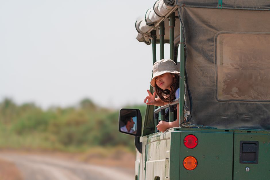 Young girl enjoying a safari ride in an open-top vehicle, exploring the wilderness.