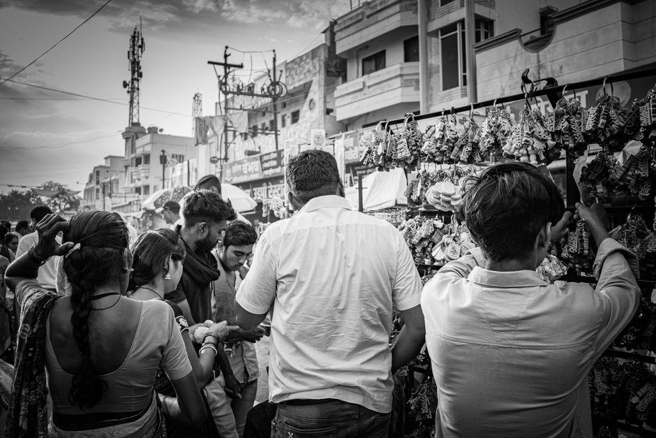 A vibrant black and white shot of a busy street market, showcasing diverse people shopping.