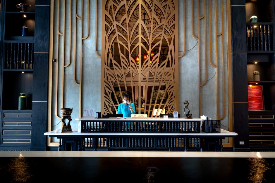 Luxurious hotel reception area with intricate design and a female receptionist at work.