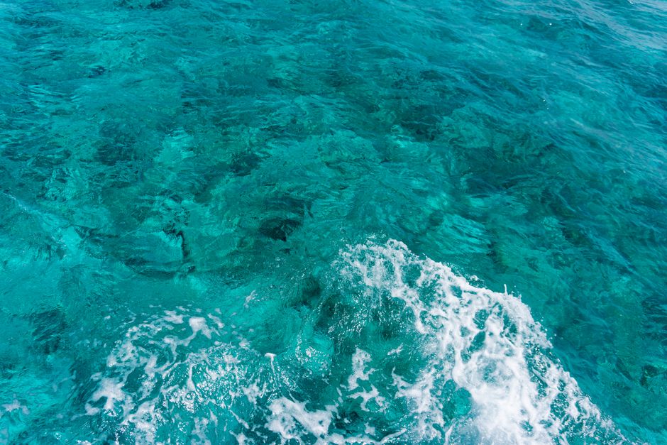 A captivating view of clear turquoise ocean waves crashing over a vibrant coral reef.