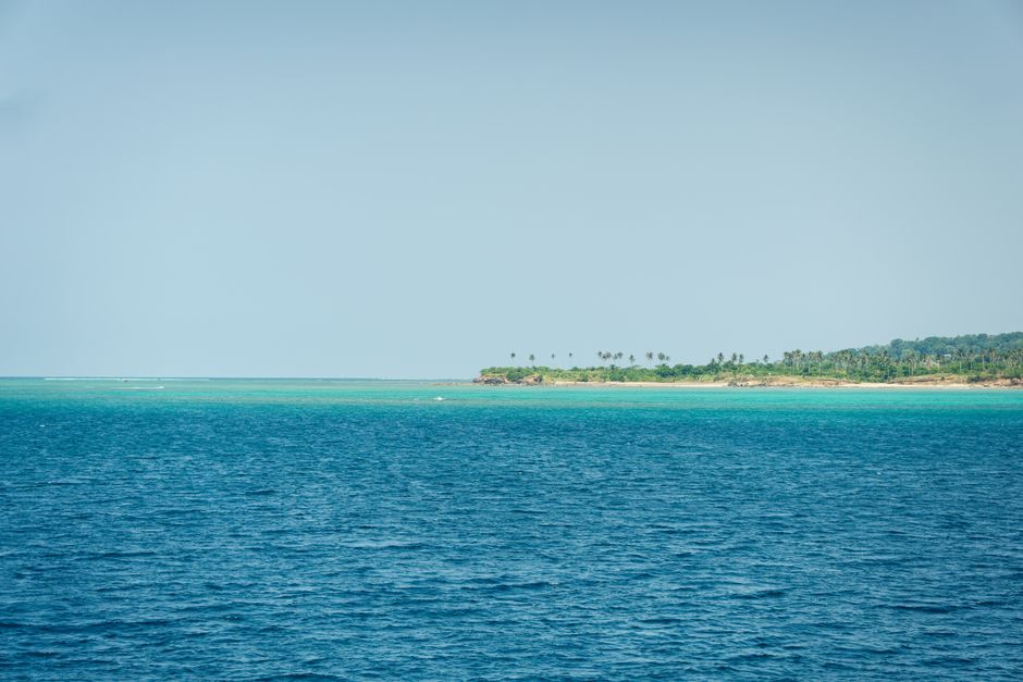 A tranquil view of a tropical island with lush greenery and clear blue ocean waters.