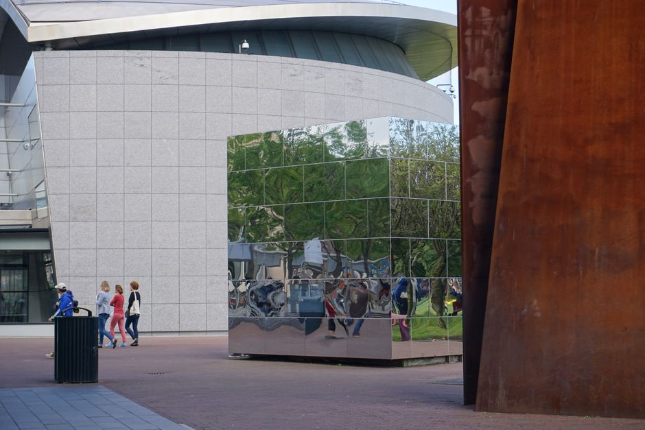 Contemporary architecture with reflective surfaces and passersby in Amsterdam.