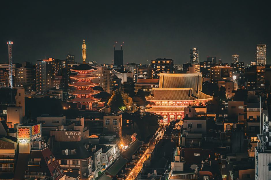 Stunning nighttime aerial view of Senso-ji Temple and Tokyo skyline in Taito City, Japan.