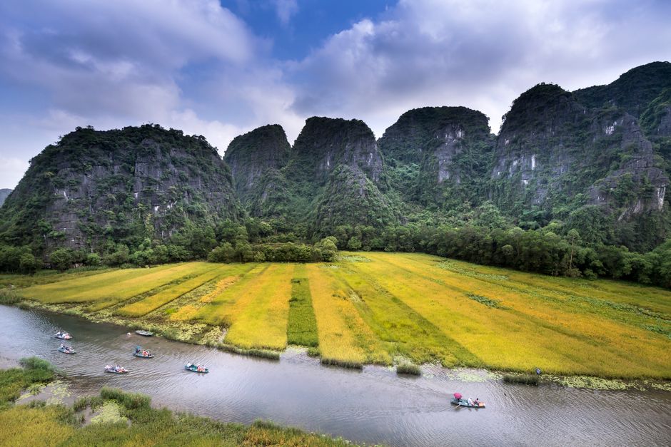 Serene landscape featuring boaters on a river with towering limestone mountains